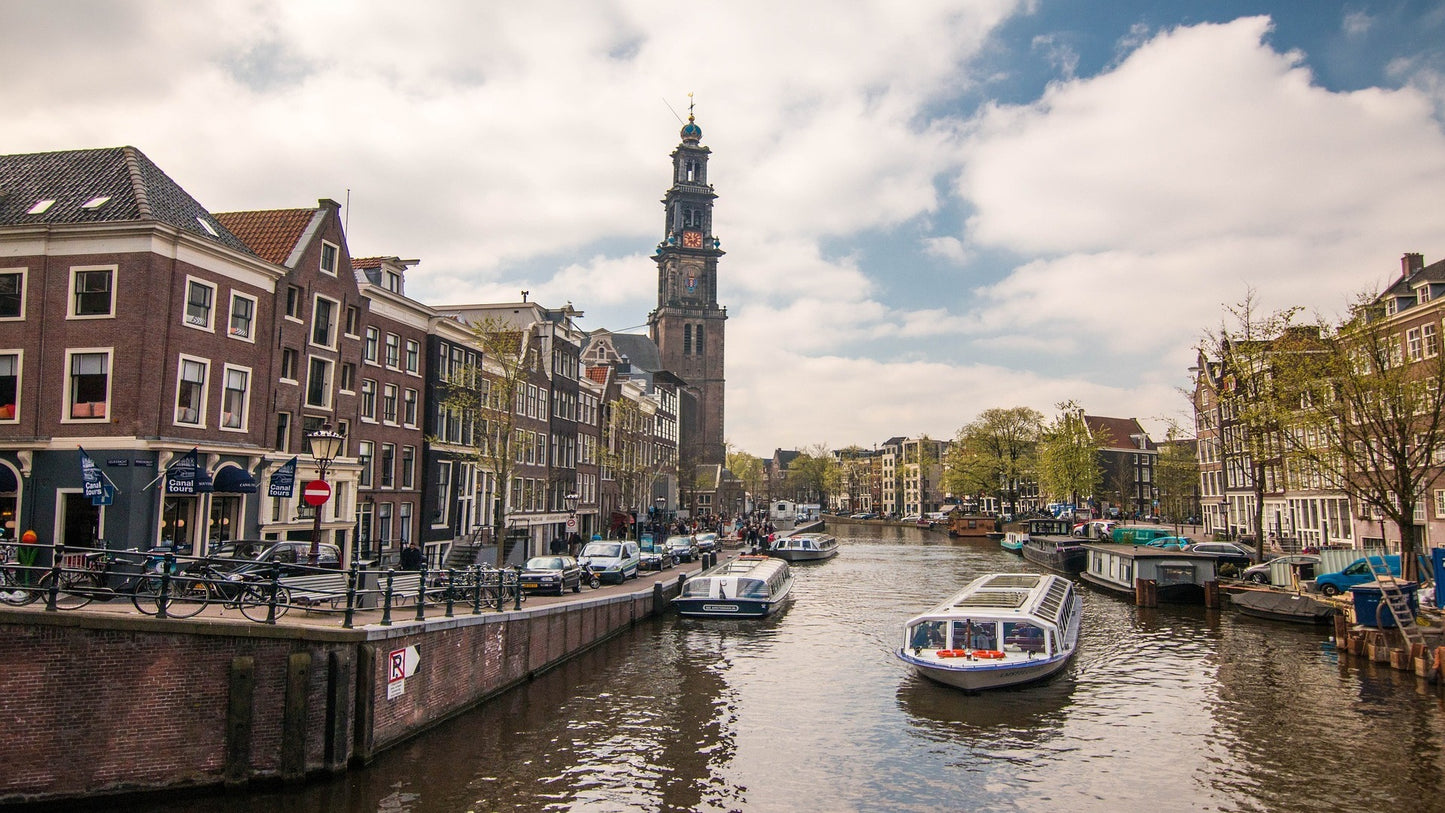 buildings in amsterdam with a riversdtreet and boats in the middle as travel target for esim